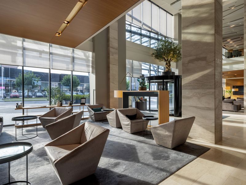 Bright multi-story building lobby with lounge seating and stone columns